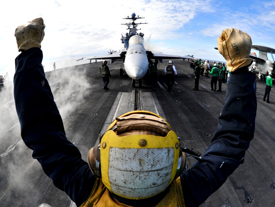 US Navy 110201-N-6003P-225 An aircraft director guides an F-A-18C Hornet onto a catapult aboard the aircraft carrier USS Harry S. Truman (CVN 75)