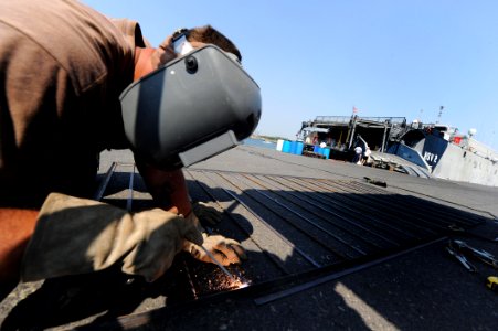 US Navy 110202-N-7589W-163 Builder 2nd Class Joshua Helton welds a fence in front of High Speed Vessel Swift (HSV 2)