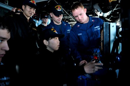 US Navy 110203-N-9818V-131 Japan Maritime Self-Defense Force Signalman 3rd Class Rika Okubo is given training by Gunner's Mate 1st Class Michael Ho
