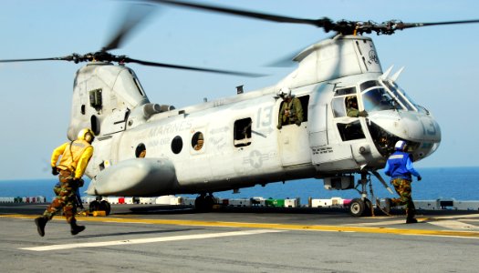 US Navy 110210-N-8607R-033 Aviation boatswain's mates prepare to remove chocks and chains from a CH-46E Sea Knight helicopter aboard the forward-de photo