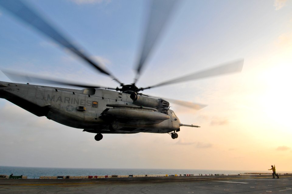 US Navy 110205-N-9950J-210 Aviation Boatswain's Mate (Handling) Airman Daniel Tesauro directs a CH-53E Sea Stallion helicopter as it lifts off aboa
