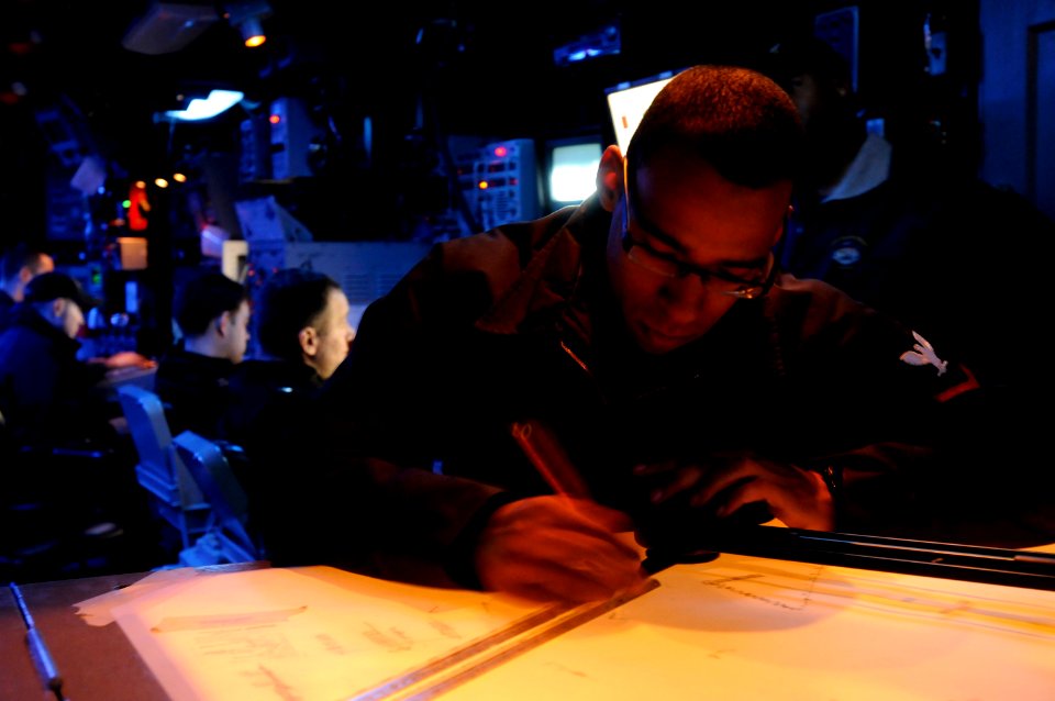 US Navy 110209-N-9094S-020 Operations Specialist 3rd Class Eric Castillo plots course markings on a digital dead reckoning tracer in the combat inf