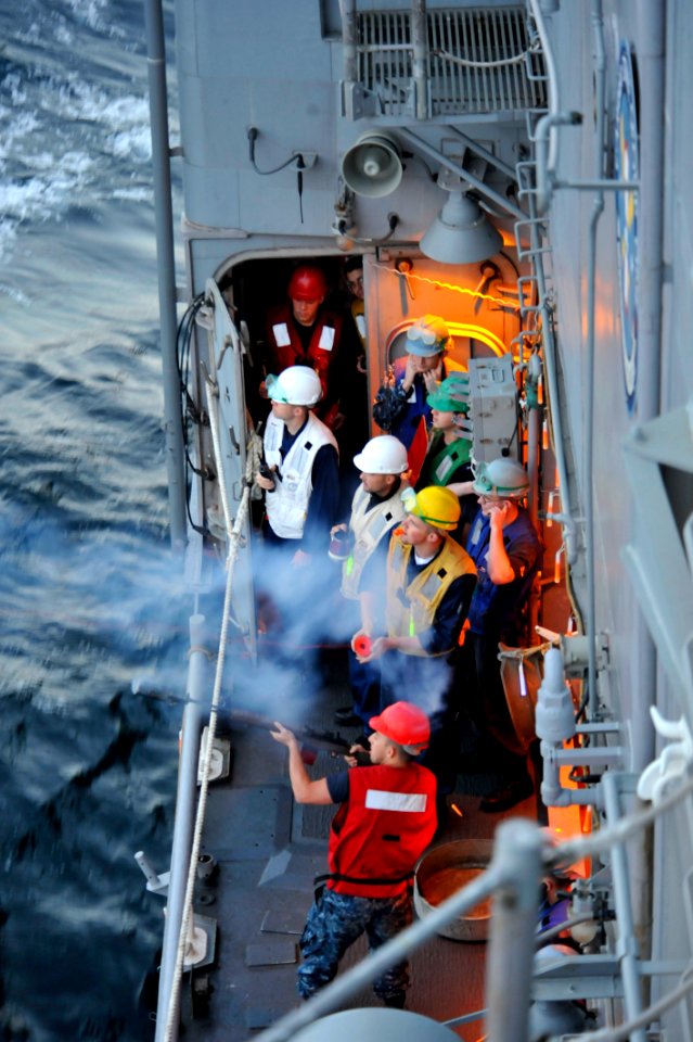 US Navy 110210-N-6006S-054 Gunner's Mate Seaman William Stafford fires a shot line from USS Bunker Hill (CG 52) to USNS Henry J. Kaiser (T-AO 187)
