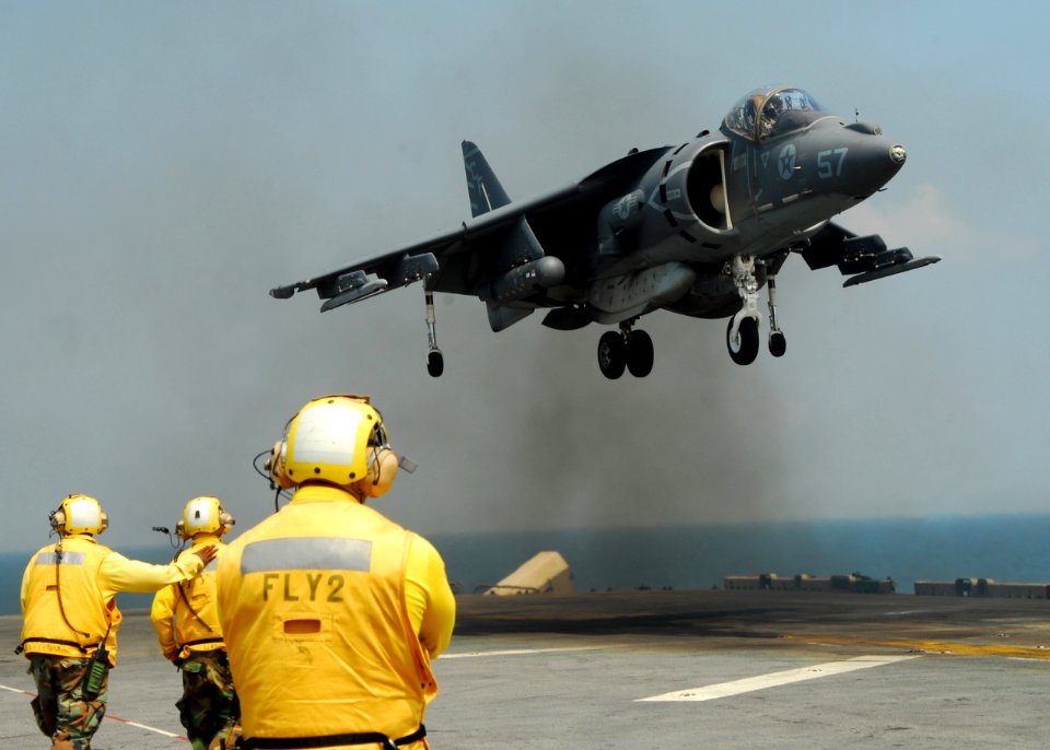 US Navy 110213-N-8607R-204 Aviation boatswain's mates watch as an AV-8B Harrier jet lands aboard the forward-deployed amphibious assault ship USS E