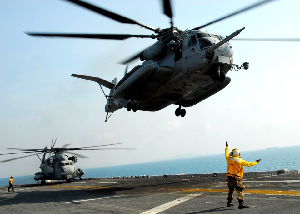 US Navy 110210-N-8607R-210 Aviation Boatswain's Mate (Handling) 3rd Class Mario Teasley directs a CH-53E Sea Stallion helicopter to take off from t