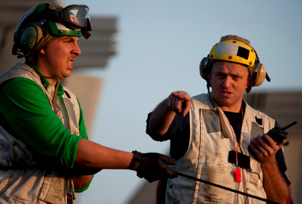 US Navy 110210-N-7981E-389 Boatswain's Mate 1st Class Robert Huxoll directs line handlers on the flight deck of the Nimitz-class aircraft carrier U