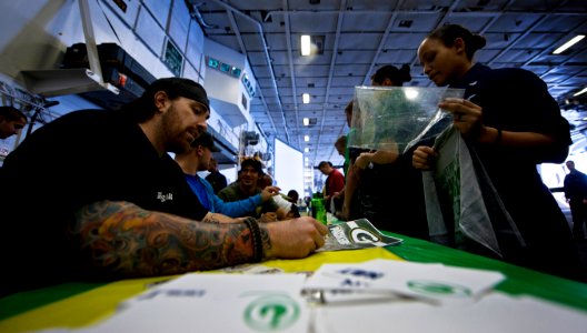 US Navy 110216-N-2055M-026 Darryn Colledge, a guard for the Green Bay Packers football team, signs an autograph for a Sailor in the hangar bay of t