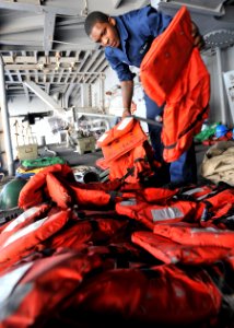US Navy 110212-N-0569K-039 Seaman Deremy J. Walker lays out K-POC life preservers on a sponson in preparation for a replenishment at sea aboard the