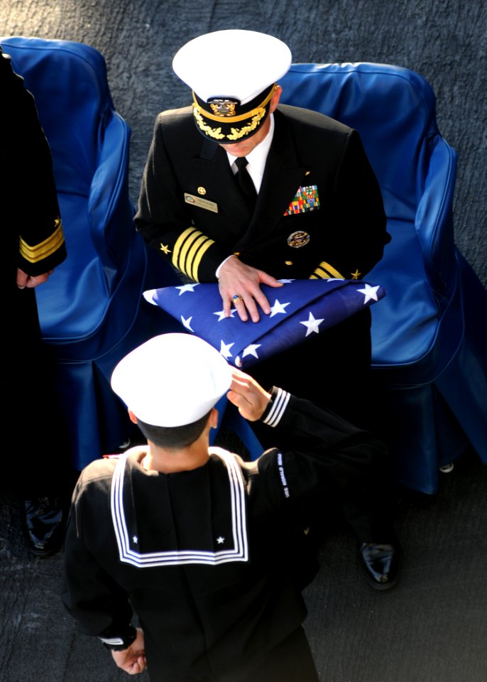 US Navy 110214-N-4590G-422 Boatswain's Mate 1st Class JRay Norris renders a salute after passing the flag to Capt. Thom Burke