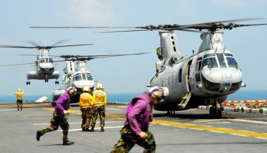 US Navy 110213-N-8607R-393 Aviation fuel crew members run to fuel a CH-46E Sea Knight helicopter aboard the forward-deployed amphibious assault shi photo