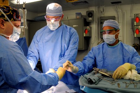 US Navy 110215-N-JD217-013 Hospital Corpsman 2nd Class Marc Maribao, right, hands Lt. Cmdr. Brian Knipp a surgical tool while training in the opera