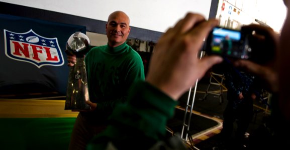 US Navy 110216-N-2055M-220 Master Chief Aviation Electronics Technician Robby Bonanno poses for a photo with the Vince Lombardi trophy in the hanga