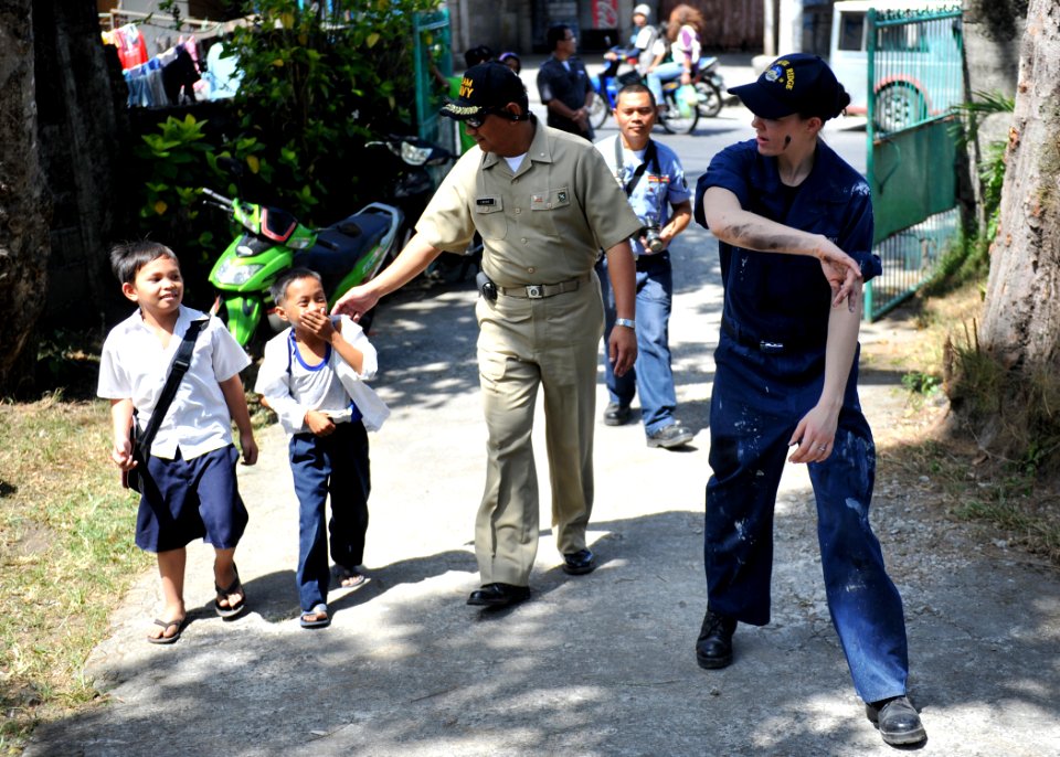 US Navy 110216-N-4031K-563 Sailors invite children to help paint a rail at the Rural Health Clinic in Cavite City for a community service project