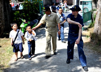 US Navy 110216-N-4031K-563 Sailors invite children to help paint a rail at the Rural Health Clinic in Cavite City for a community service project
