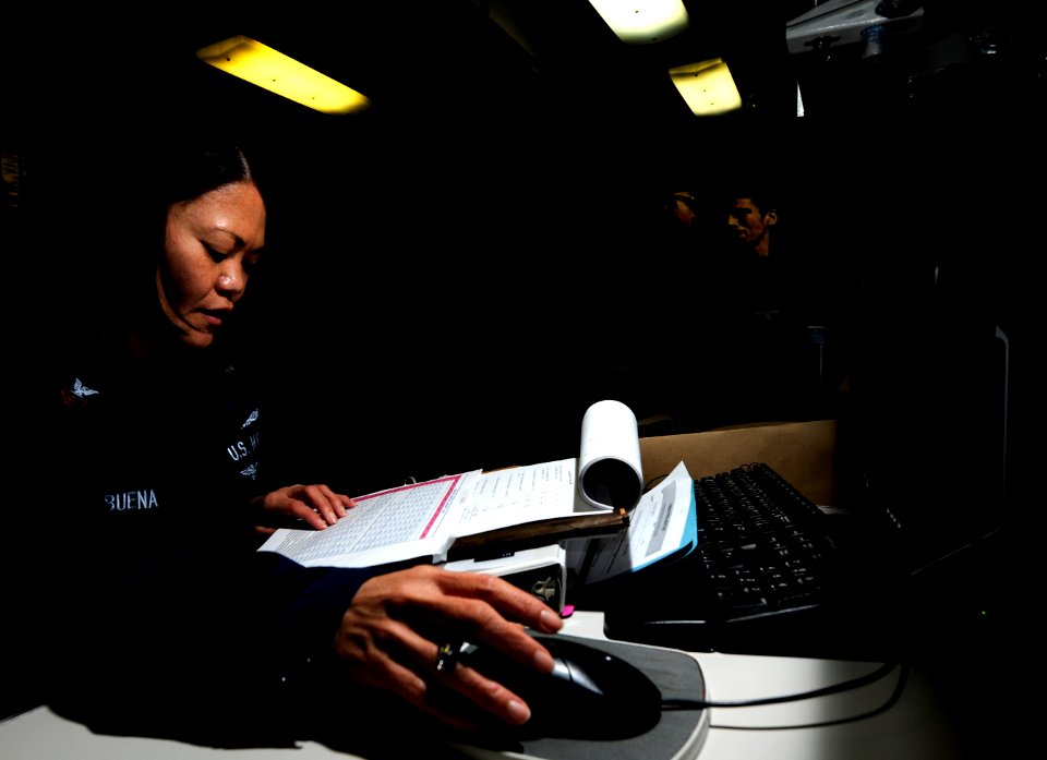 US Navy 110216-N-8040H-152 Personnel Specialist 1st Class Marietta Balbuena calculates a selective re-enlistment bonus for personnel in the flag ad