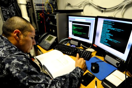 US Navy 110216-N-8040H-109 Information Systems Technician 1st Class Victor Morquecho reads an information systems manual in the flag communications