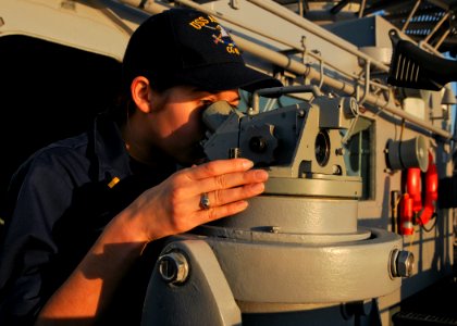 US Navy 110220-N-9793B-005 Ensign Leah M. Fontenot looks through a telescopic alidade on the ship's port bridge wing aboard the guided-missile crui