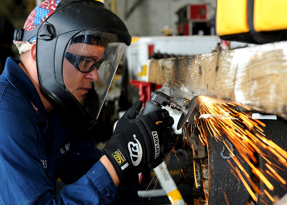 US Navy 110226-N-2908M-017 Aviation Structural Mechanic 2nd Class Jason Jacobs grinds a weld on a tow bar trailer aboard the amphibious assault shi