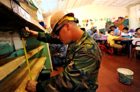 US Navy 110221-N-EC642-402 Builder 1st Class Clifton Horn takes measurements of book shelves at Centro Escolar Republica de Honduras during a weekl