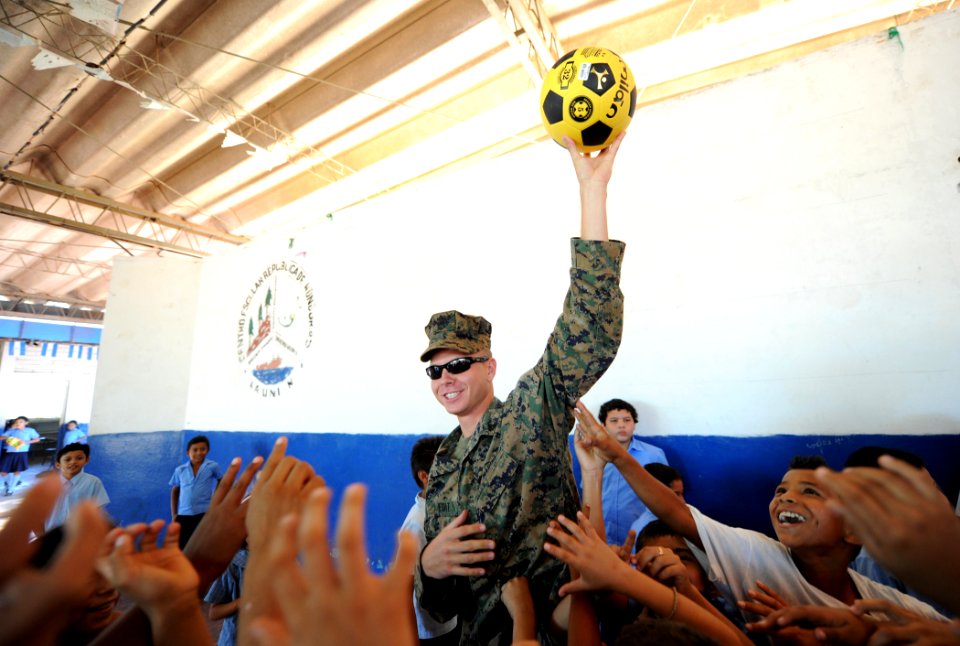 US Navy 110228-N-EC642-076 Cpl. Paul Fuit, assigned to 2nd Marine Logistics Group, presents a soccer ball to students during a Southern Partnership