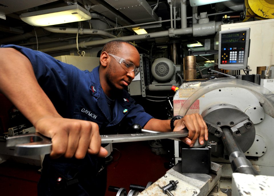 US Navy 110228-N-0569K-020 Machinery Repairman 2nd Class Pernail M. Gaymon uses a lathe to make a spindle for a spotting dolly aboard the aircraft