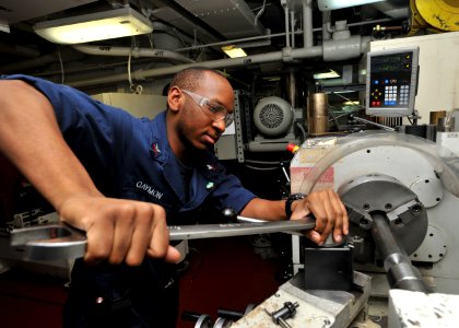US Navy 110228-N-0569K-020 Machinery Repairman 2nd Class Pernail M. Gaymon uses a lathe to make a spindle for a spotting dolly aboard the aircraft