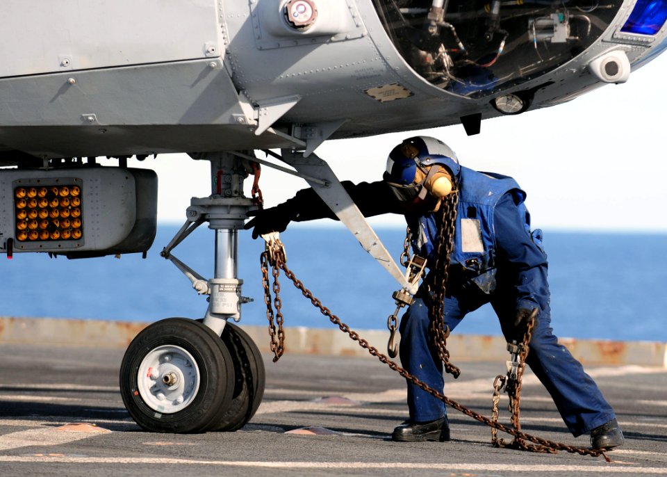 US Navy 110225-N-RC734-165 Boatswain's Mate 3rd Class Lakeiha Henderson, from New York, removes a tie-down chain from the nose wheel of a CH-46E Se