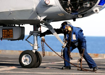 US Navy 110225-N-RC734-165 Boatswain's Mate 3rd Class Lakeiha Henderson, from New York, removes a tie-down chain from the nose wheel of a CH-46E Se