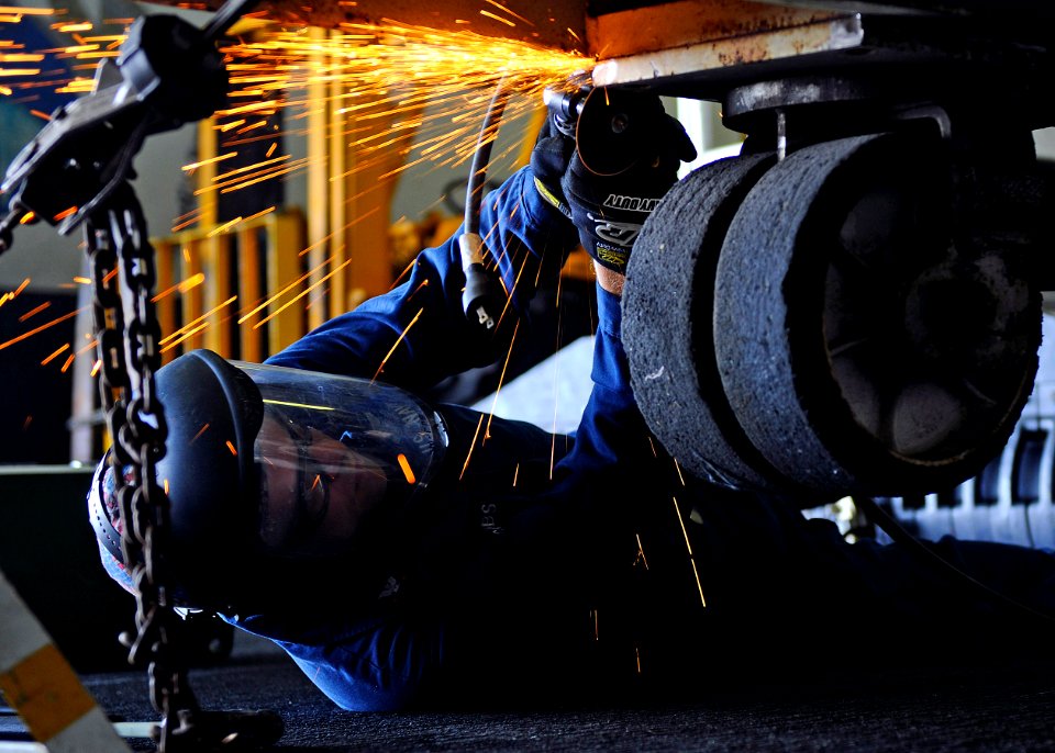 US Navy 110226-N-3154P-123 Aviation Structural Mechanic 2nd Class Jason Jacobs uses a high-speed cutting tool to remove part of an aircraft tow-bar