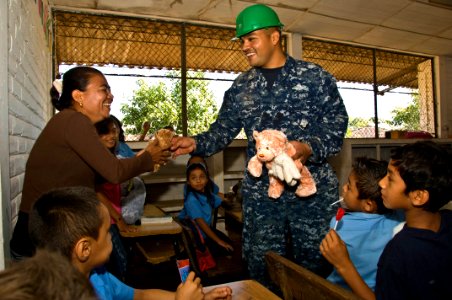 US Navy 110222-N-UX336-019 Hospital Corpsman 2nd Class Robert Medina hands a stuffed animal to a teacher at Centro Escolar Republica de Honduras