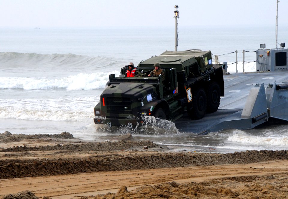 US Navy 110304-N-1786N-016 A Marine drives a medium tactical vehicle replacement vehicle onto the beach during roll-on-roll-off discharge facility