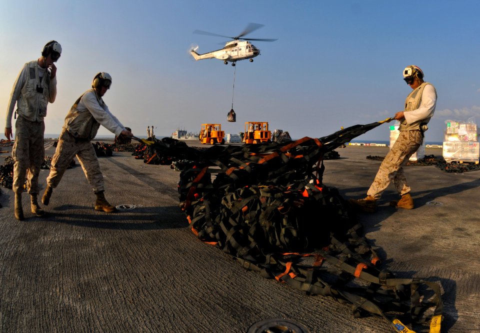 US Navy 110225-N-9950J-345 Lance Cpl. Dan Canada, left, and Lance Cpl. Carlos Mendoza move cargo nets as an SA-330J Puma helicopter drops off suppl
