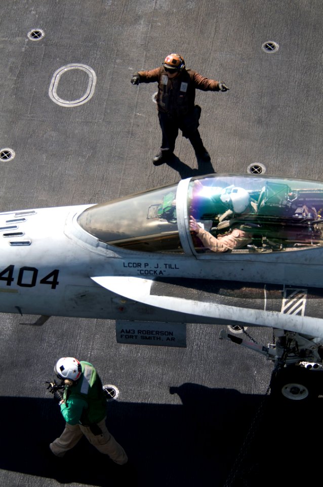 US Navy 110307-N-7488A-443 A plane captain guides the pilot of an F-A-18C Hornet through pre-flight checks aboard USS Carl Vinson (CVN 70)