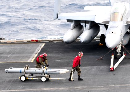 US Navy 110308-N-DM338-105 Marines assigned to the Death Rattlers of Marine Fighter Attack Squadron (VMFA) 323, move ordnance on the flight deck of