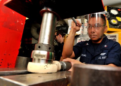 US Navy 110304-N-0569K-012 Aviation Structural Mechanic 3rd Class Ricardo Beltrano uses a hydraulic press to replace a bearing from a swivel adapt