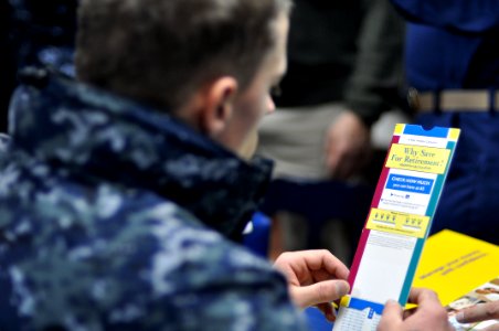 US Navy 110304-N-SF508-025 Fire Controlman 2nd Class Karl Weber reads a pamphlet about how to save for retirement during a Military Saves Campaign