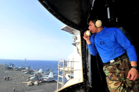 US Navy 110306-N-3852A-011 Aviation Boatswain's Mate (Handling) Airman Michael Lira communicates with the ship's aircraft handling officer while st
