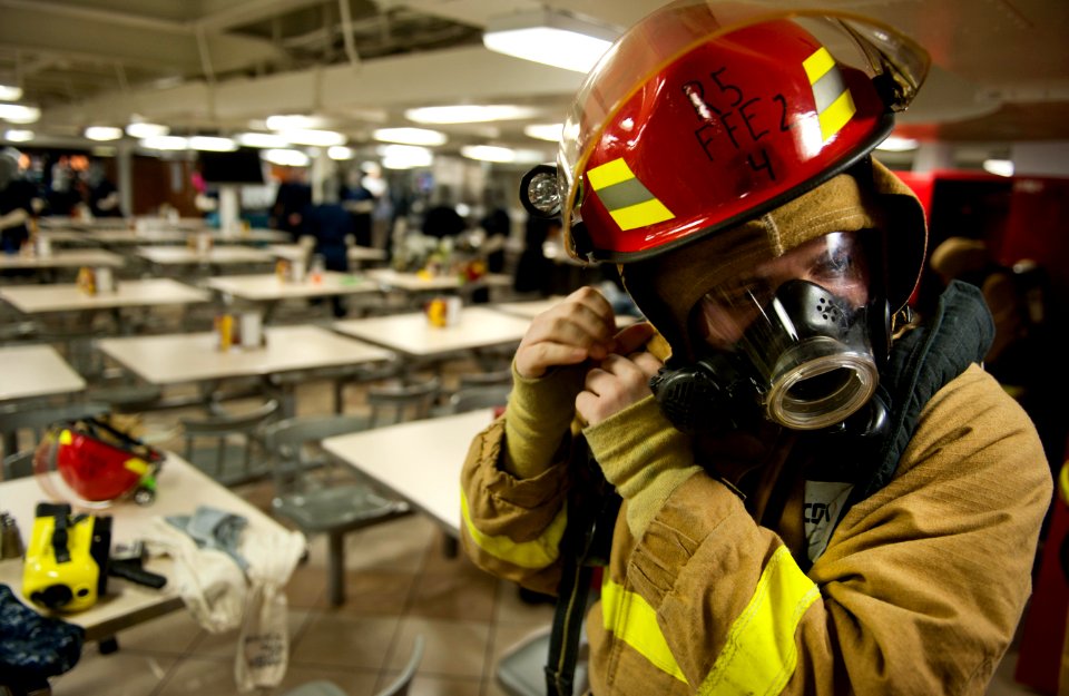 US Navy 110312-N-DR144-091 Machinist's Mate 2nd Class Joseph Pontoriero dons a firefighting ensemble on the mess decks during a general quarters dr