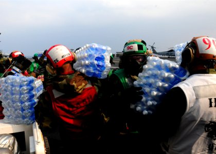 US Navy 110314-N-5503T-113 Sailors move cases of drinking water to helicopters on the flight deck of the aircraft carrier USS Ronald Reagan (CVN 76