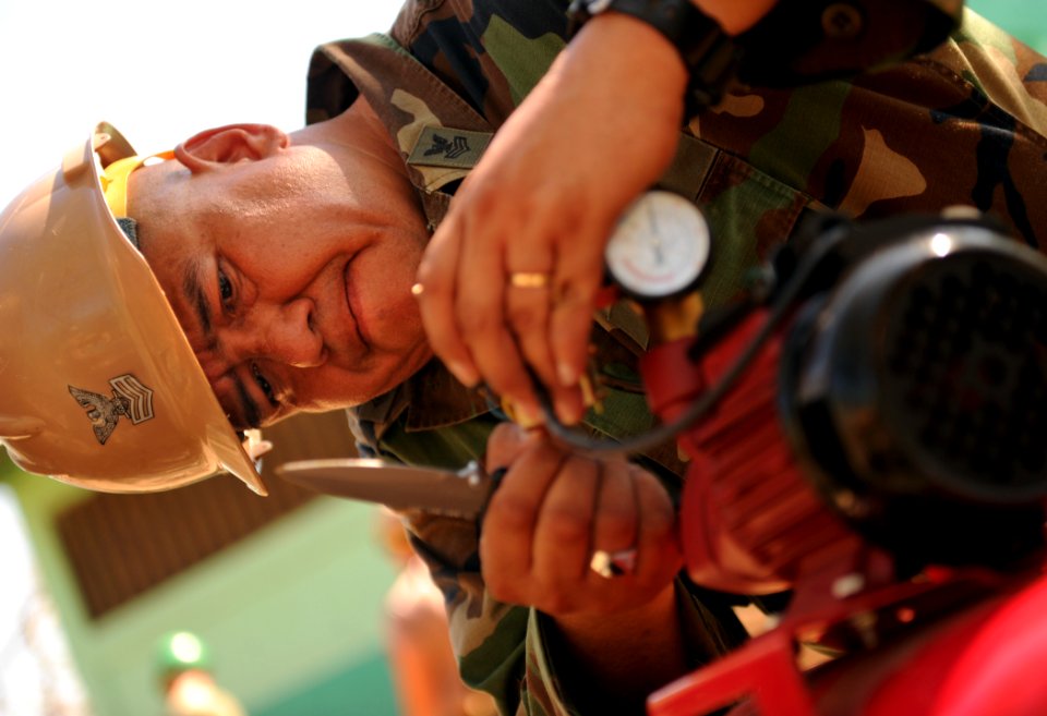 US Navy 110314-N-EC642-475 Utilitiesman 1st Class Carlos Sanchez prepares a water pump for installation at Escuela Eneas Alvarado during a week-lon