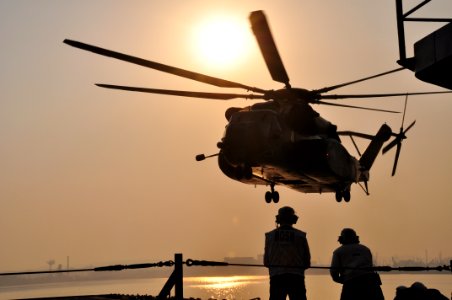 US Navy 110312-N-3999C-096 Chief Warrant Officer Steve Metham and Senior Chief Damage Controlman David Hernandez observe an MH-53 helicopter approa