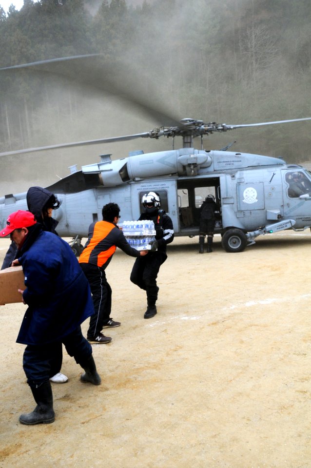 US Navy 110315-N-IC111-125 Chief Naval Air Crewman Steven Sinclair hands bottled water to a Japanese citizen