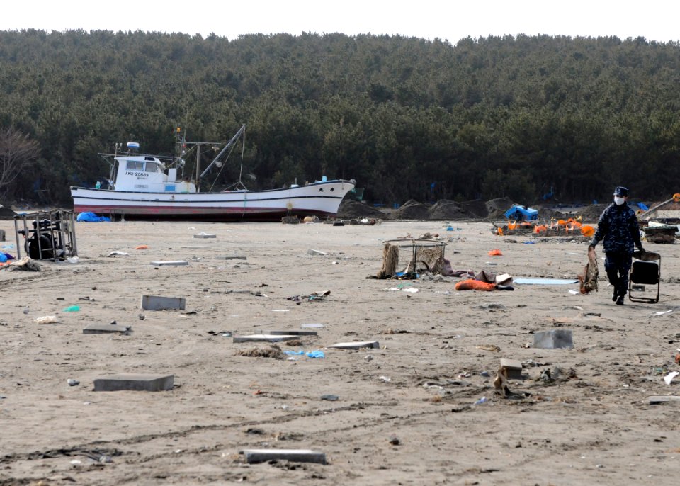 US Navy 110314-N-MU720-088 A Sailor assigned to Naval Air Facility Misawa carries debris to a dumpsite during a cleanup effort at the Misawa Fishi