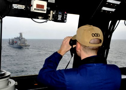 US Navy 110315-N-2147L-004 Officer of the Deck Lt. j.g. Timothy Gorman observes the Military Sealift Command fleet replenishment oiler USNS John Le