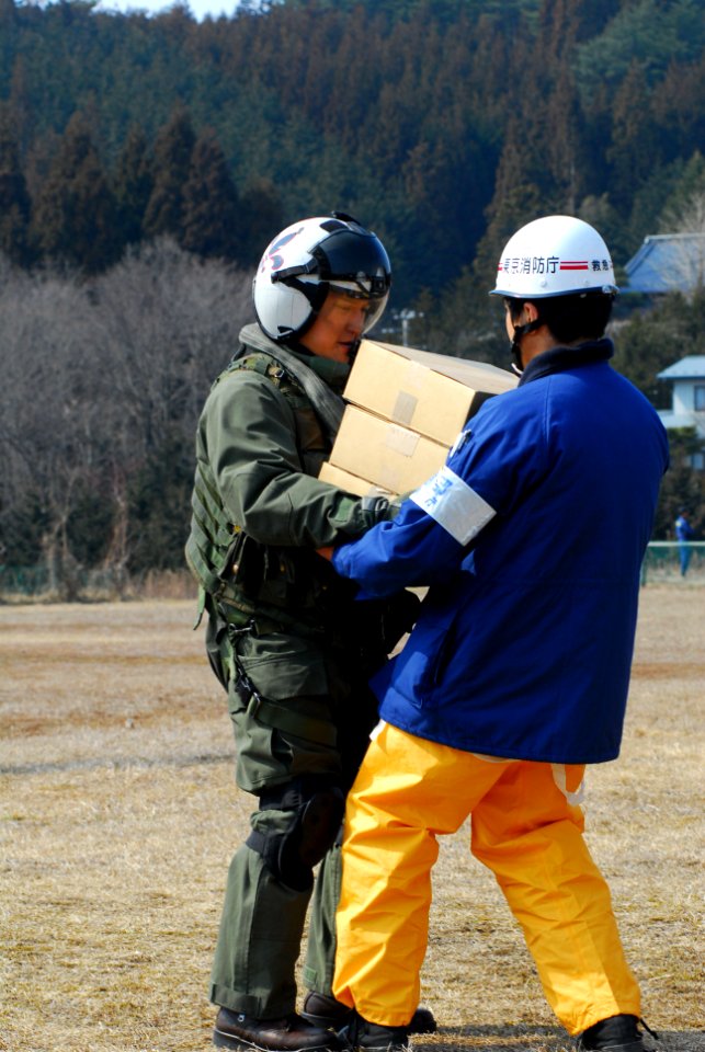US Navy 110313-N-SB672-014 Lt. Cmdr. Albin Quinko hands over supplies to a Japanese aid worker during earthquake and tsunami relief efforts near S