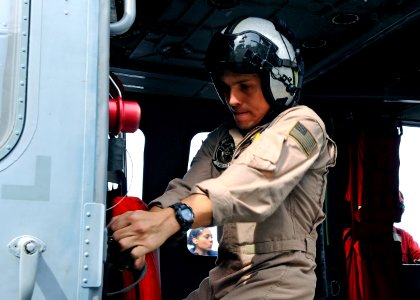 US Navy 110317-N-3154P-075 Naval Air Crewman 2nd Class Christopher Sahagun tightens the restraints inside a MH-60S Sea Hawk helicopter