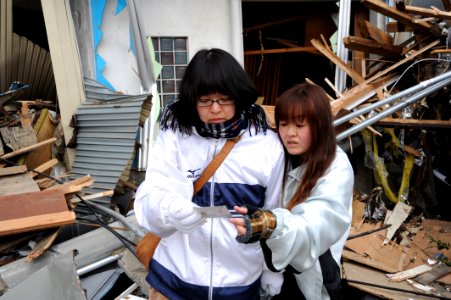 US Navy 110315-N-2653B-138 A mother and daughter look at a family photo amid the wreckage of their home
