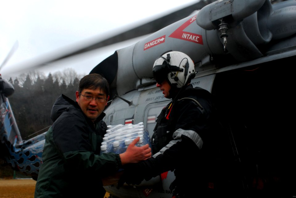 US Navy 110316-N-SB672-137 Naval Air Crewman 3rd Class Seth Eslin gives cases of water to Japanese citizens during a humanitiarian assistance missi