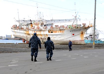 US Navy 110317-N-MU720-023 Sailors assigned to Naval Air Facility Misawatake walk towards a fishing boat that washed ashore in a tsunami caused by