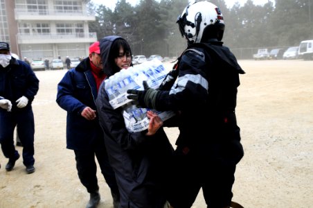 US Navy 110315-N-IC111-117 Naval Air Crewman 2nd Class Zack DelCorte ands bottled water to a Japanese citizen